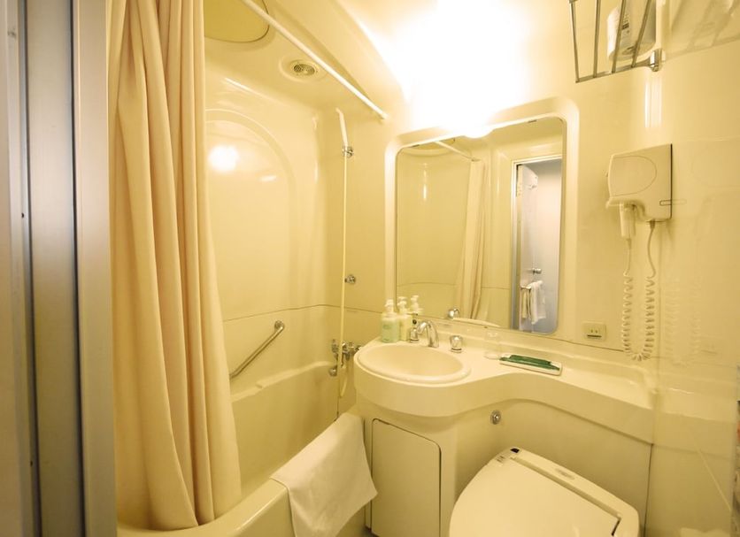 Route Inn Grantia Komaki bathroom with compact shower-tub, sink, mirror, and toilet in Komaki