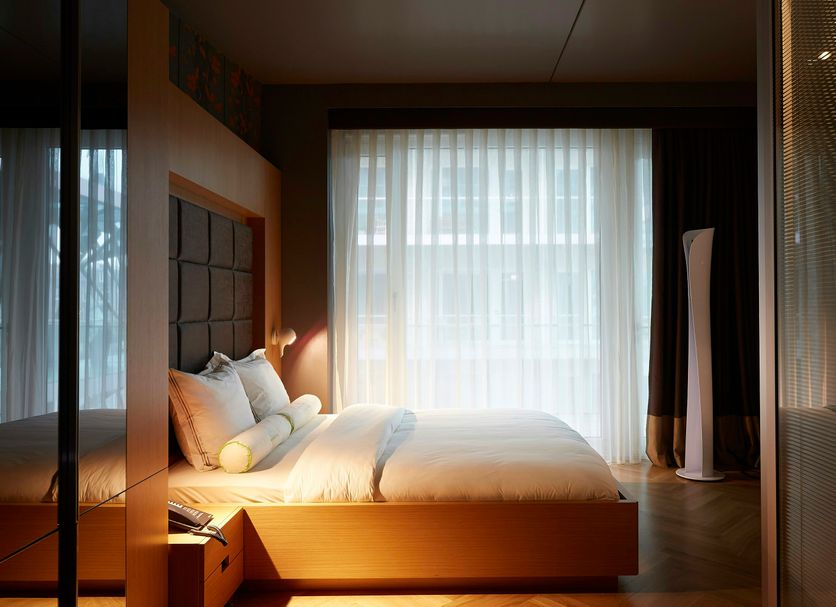 Amadi Park Hotel Amsterdam guest room with king bed, sheer curtains and warm ambient lighting