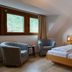 Hotel Kachelburg in Dieblich guest room with twin beds, armchairs, and a window view of greenery