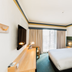 Statesman Hotel Canberra guest room with king bed, desk, wall-mounted TV and sheer-curtained window