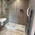 The Churchill Court, Woodstock: compact hotel bathroom with shower, wall-mounted sink, toilet and heated towel rail.