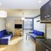 Aparthotel Adagio Access Palaiseau Saclay room with blue sofas, kitchenette, and sunlit window in Palaiseau
