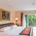 Jomtien Beach Residence in Pattaya guest room with balcony view of lush greenery and sliding glass doors