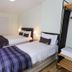 Hillhead Farm Lets in Stirling bedroom with two twin beds, plaid throws, and open clothing rack