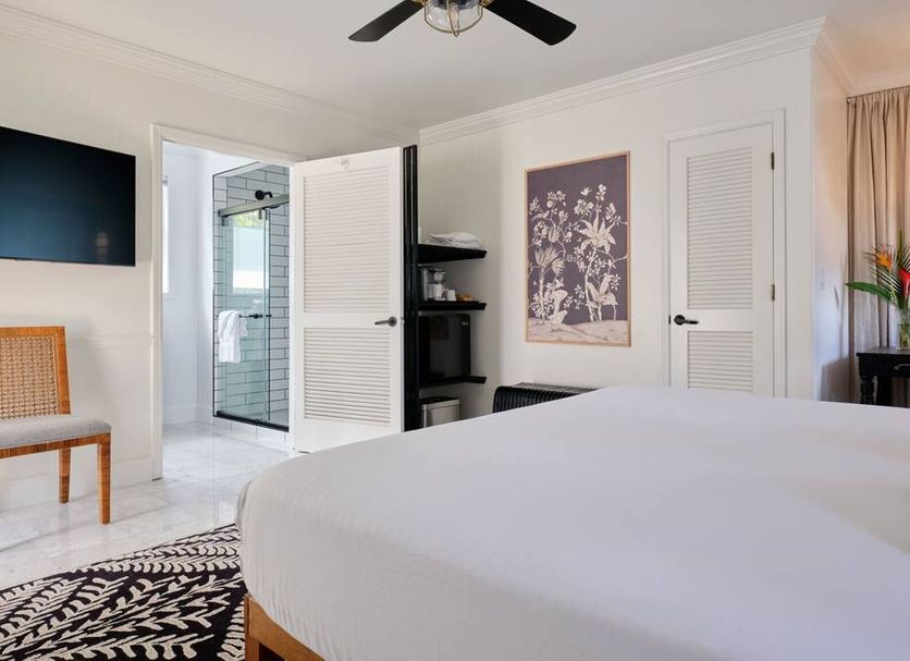 The Historic Wailuku Inn bedroom with en suite bathroom, ceiling fan, and floral wall art in Wailuku