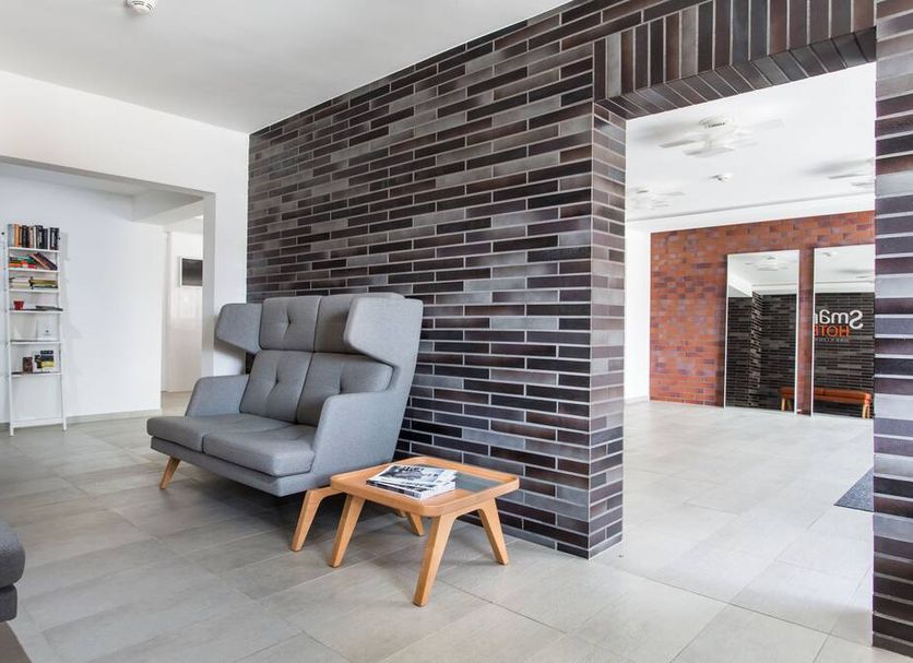 Smart Hotel Gdansk lobby seating area with gray chair, small table and brick accent wall