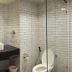 The Royal City Hotel Bangkok bathroom with glass shower, white subway tile, and wall-mounted sink