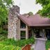 The Inn at Little Sister Hill in Sister Bay, stone chimney entrance surrounded by trees and greenery