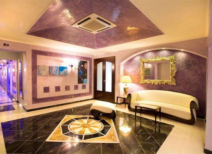 Hotel Garibaldi Milazzo lobby with glossy tiled floor, cream seating, ornate mirror and purple ceiling
