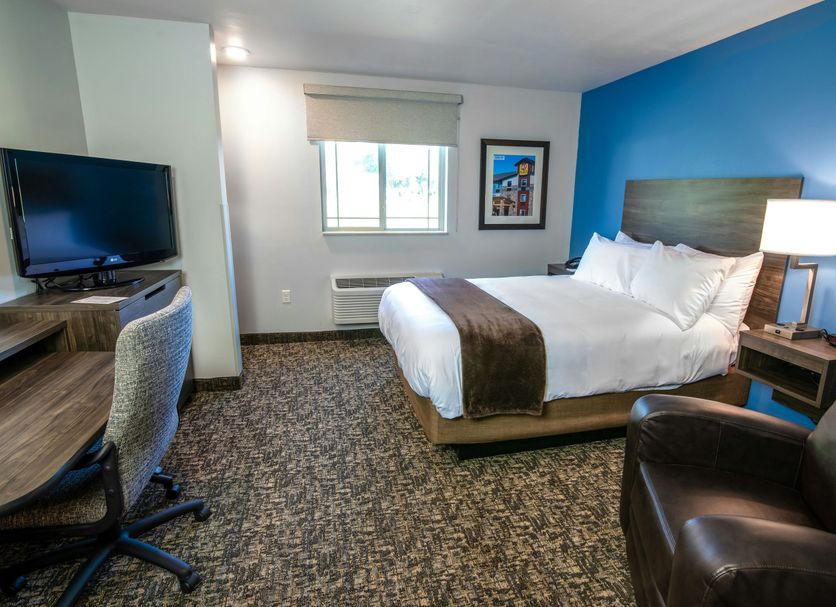 My Place Hotel-Carson City, Nv guest room with queen bed, desk, TV, chair and bright blue accent wall in Carson City