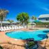 NRMA Ballarat Holiday Park poolside area with turquoise pool, loungers, palm trees and blue sky in Ballarat