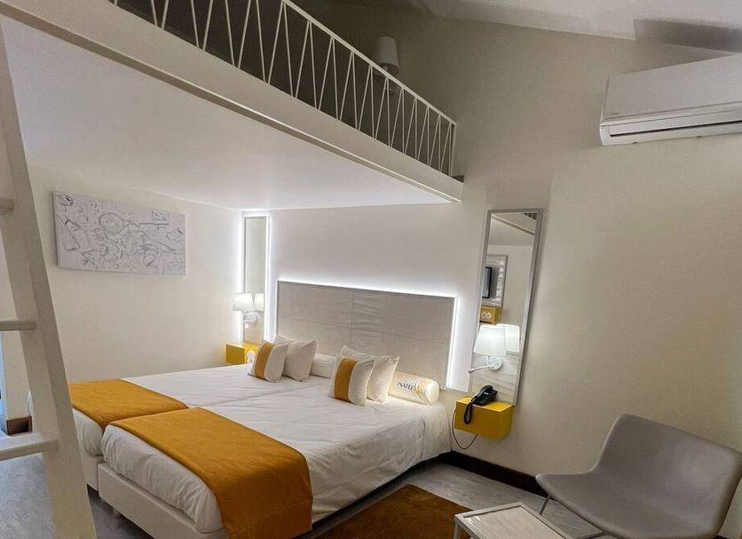 Inatel Oeiras room with double bed, loft-style mezzanine, wall mirror and air conditioner in Oeiras