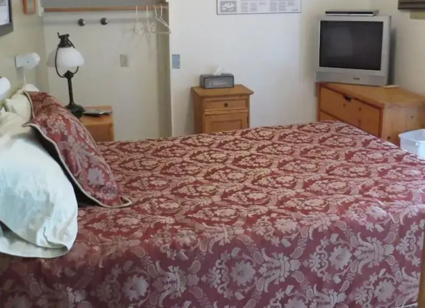 Tofino Swell Lodge guest room with bed, TV, dresser and wall art in Tofino
