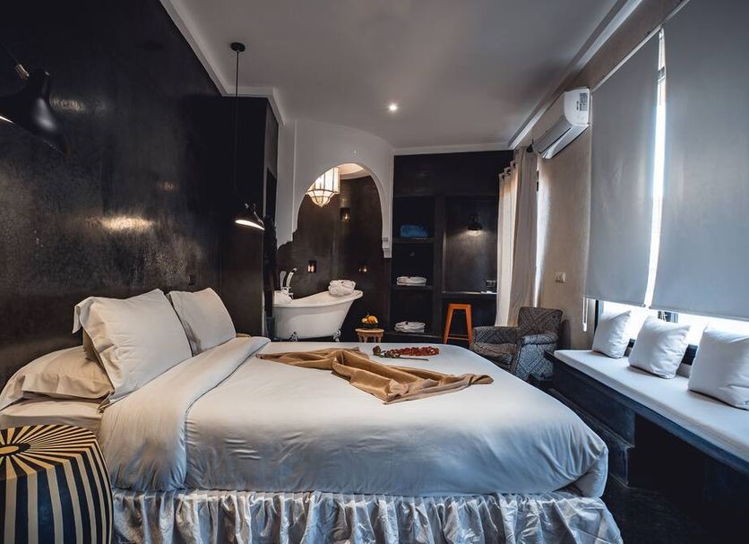 Ambre Epices Medina Riad in Marrakech guest room with bed, sofa seating, and ornate bathroom arch