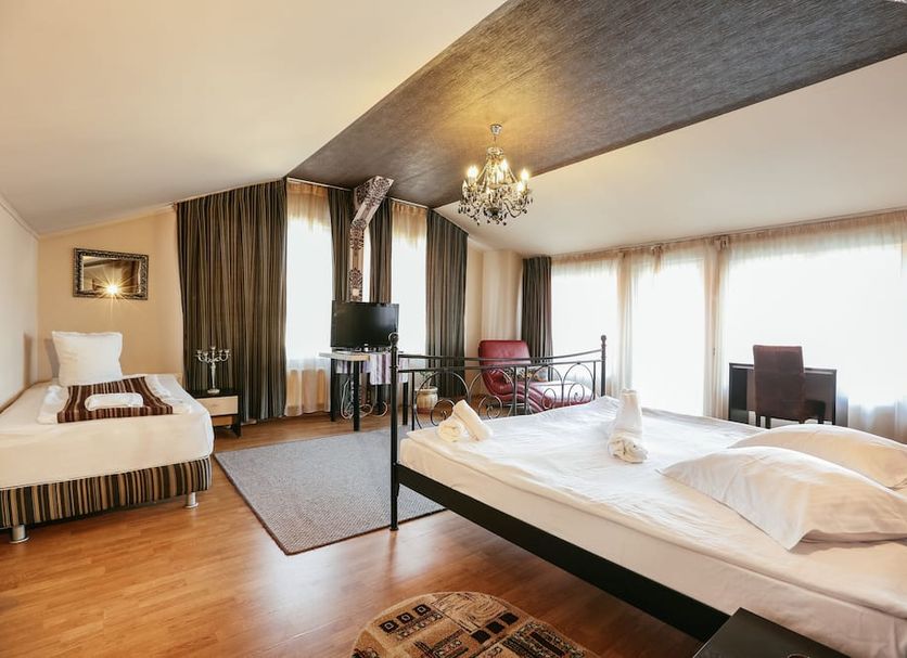 Vila Vidalis Cluj Napoca room with two beds, chandelier, and large windows with sheer curtains