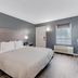 Quality Inn Laurinburg guest room with king bed, gray walls, bedside lamps, and window air unit