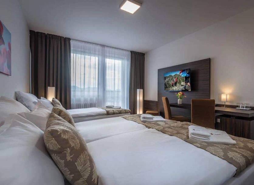Hotel Satel, Poprad guest room with two beds, desk, TV and large window