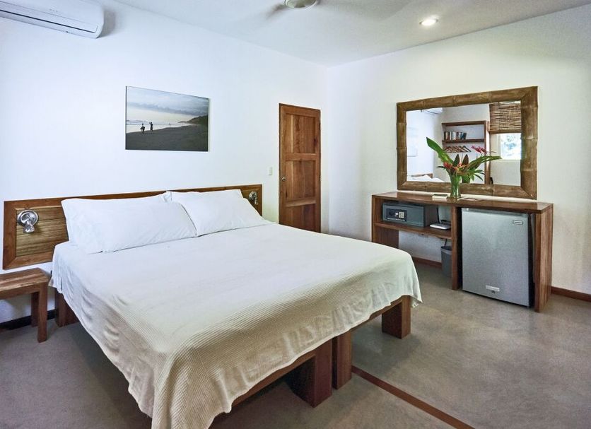 Otro Lado Lodge And Restaurant room in Santa Teresa with king bed, desk, mirror and mini fridge