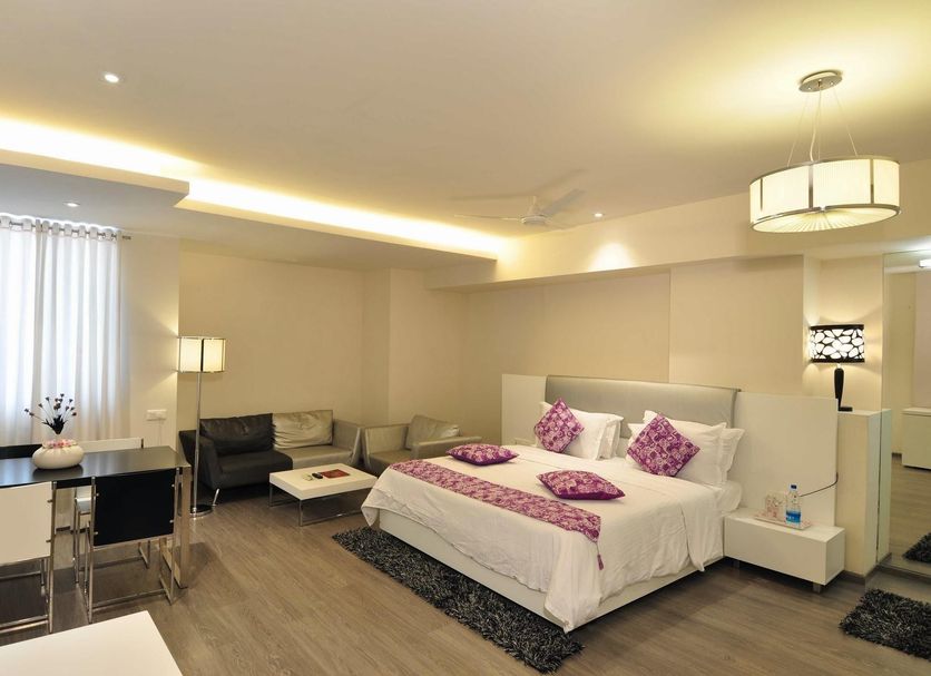 Hotel Vijay Parkinn, Coimbatore guest room with king bed, sofa, desk, and warm lighting