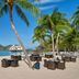 The St. Regis Langkawi beachside dining area with palm trees, tables on sand, and ocean views