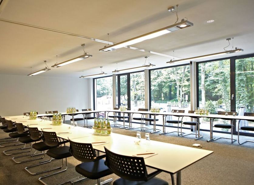 V-Hotel Bonn meeting room with long conference table and large windows overlooking trees