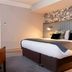 Greswolde Arms by Chef & Brewer Collection in Solihull bedroom with king bed, leather chair and archway