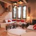 Le Jardin Des Douars in Essaouira: cozy lounge with curved staircase, sectional seating, fireplace, and tall windows