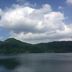 Minshuku Unagi Kohan in Ibusuki with a calm lake and green mountains under cloudy sky