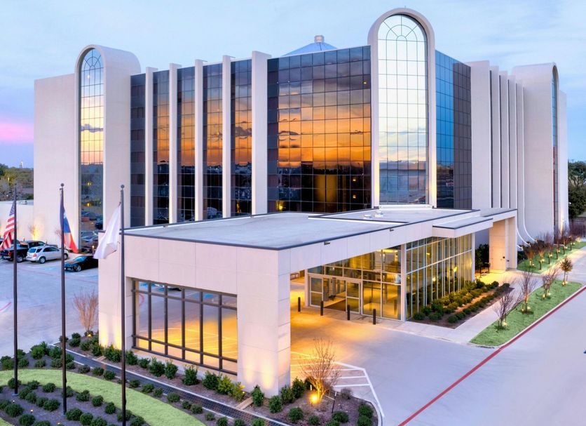 The Lamar in Arlington exterior at dusk with glass facade, arched windows, and lit entrance