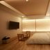 Hotel East9 in Gangneung guest room with bed, wall-mounted TV, chairs, and warm wood flooring