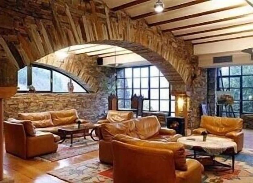 La Rectoral in Taramundi stone lounge with leather sofas, arched ceiling, and large windows