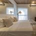 Frangipani Hotel Boutique in Brotas guest room with king bed, wall-mounted TV, and balcony curtains