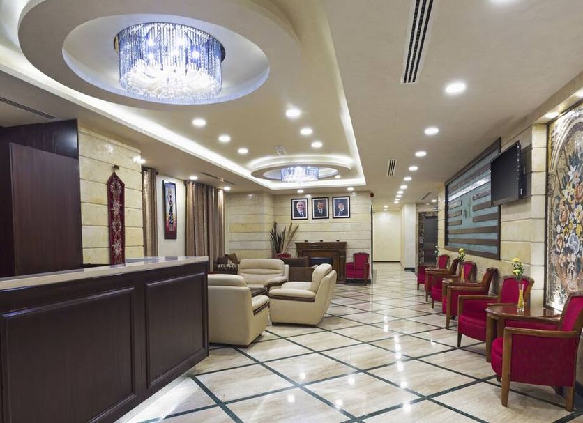 Olive Hotel Amman lobby in Amman with chandelier lighting, red armchairs, and marble tile flooring
