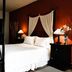 Hacienda La Magdalena in Zapopan bedroom with canopy bed, dark wood nightstands and warm red walls