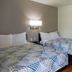 Motel 6 Lufkin guest room with two beds, wall lamp, and wood-look flooring