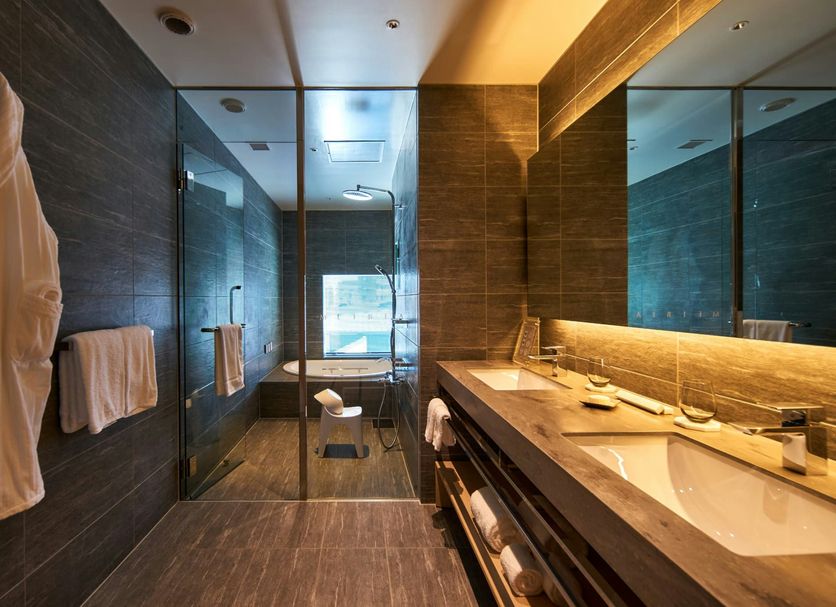 The Meibia Miyazaki bathroom with double vanity, walk-in glass shower, and towel robes in Miyazaki