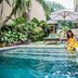 O Villas Seminyak in Kuta: woman sitting beside a private villa pool with lounge chairs and umbrella