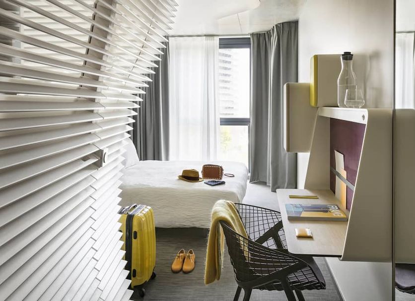 Okko Hotels Paris Porte de Versailles guest room with bed, desk, suitcase and window curtains in Paris