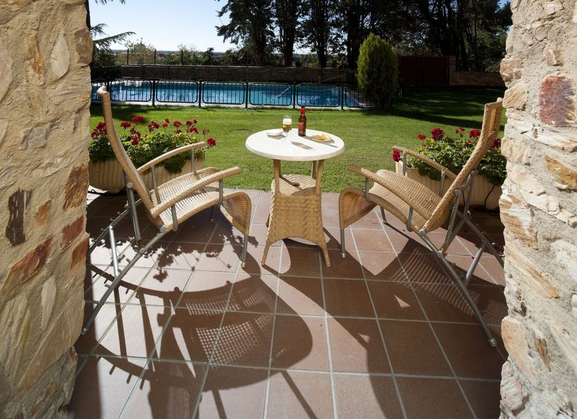 Parador De Benavente in Benavente: patio with table, chairs, and pool view through stone archway