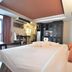 The Heritage Sathorn Suite Hotel Bangkok room with king bed, sitting area, and dark wood cabinets