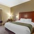 Comfort Inn & Suites Cave City guest room with king bed, bedside lamps, chair, and window curtains