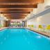Indoor pool at Home2 Suites by Hilton New Brunswick with bright seating and wood beam ceiling