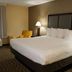 Baymont by Wyndham Bridgeport/Frankenmuth guest room with king bed, chair, lamp and window in Bridgeport