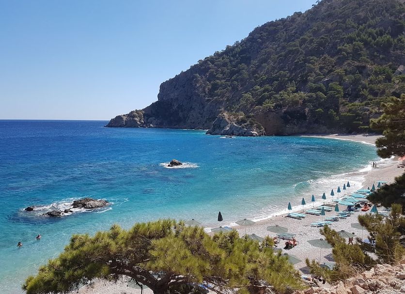 Arkasa Palace in Arkása with sea-view bay, sandy beach, turquoise water, and hillside coastline