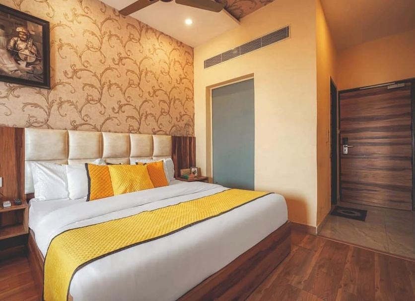 Sallow Royal Suites by Dew Drop in Amritsar features a king bed with yellow accents and wood flooring.
