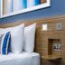 Travelodge London Twickenham guest room with bed, striped pillow, wood headboard and wall art