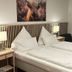 Landhotel Ewerts, Nuerburg: twin beds with white bedding, bedside lamps, and a cow wall art print