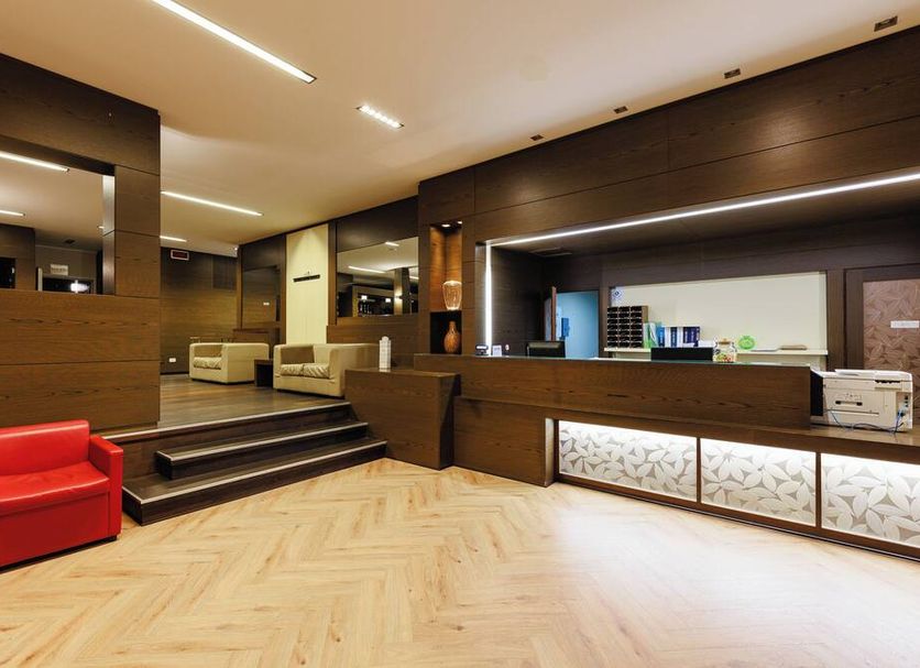 Hotel Villa Delle Rose - Malpensa lobby in Oleggio with wood reception desk, red chair and seating area