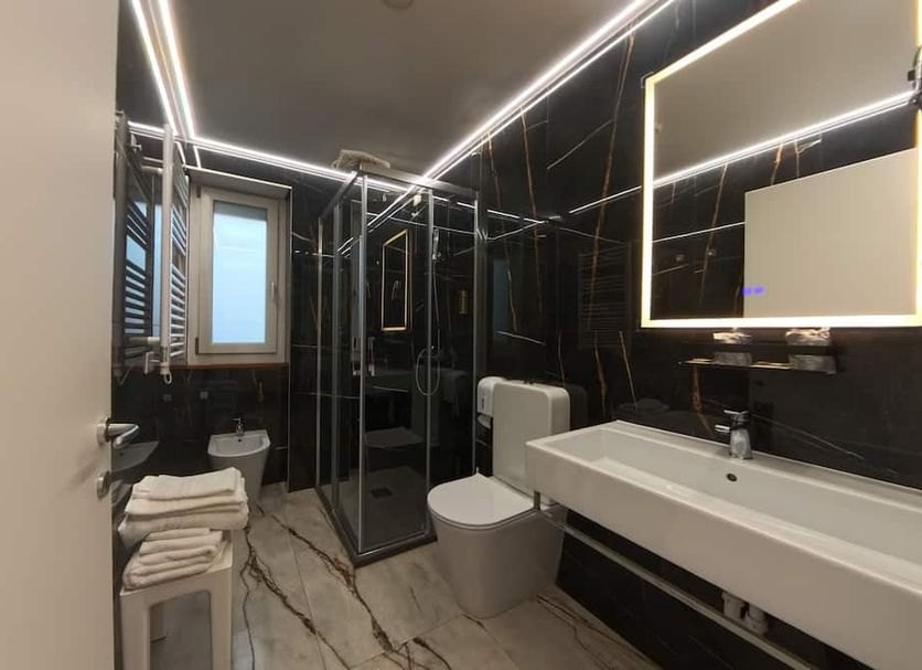 Hotel Aurora Tivoli bathroom with walk-in glass shower, vanity sink, toilet and heated towel rack