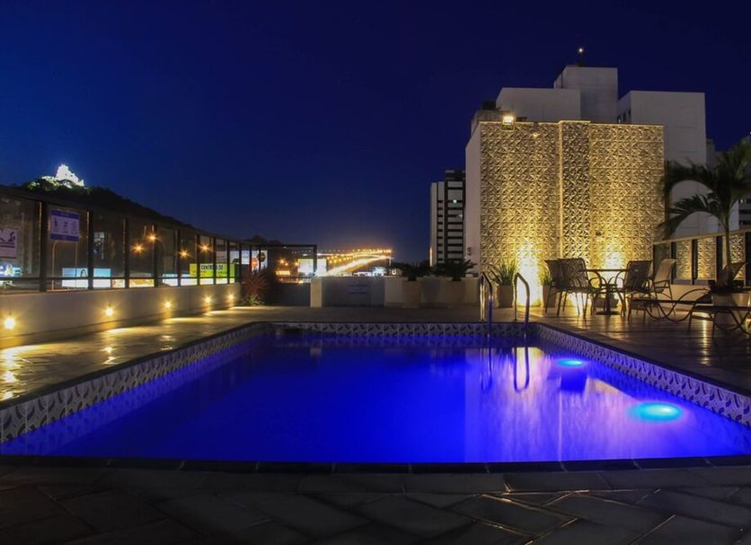 Champagnat Praia in Vila Velha: rooftop pool lit at night with lounge chairs and city skyline